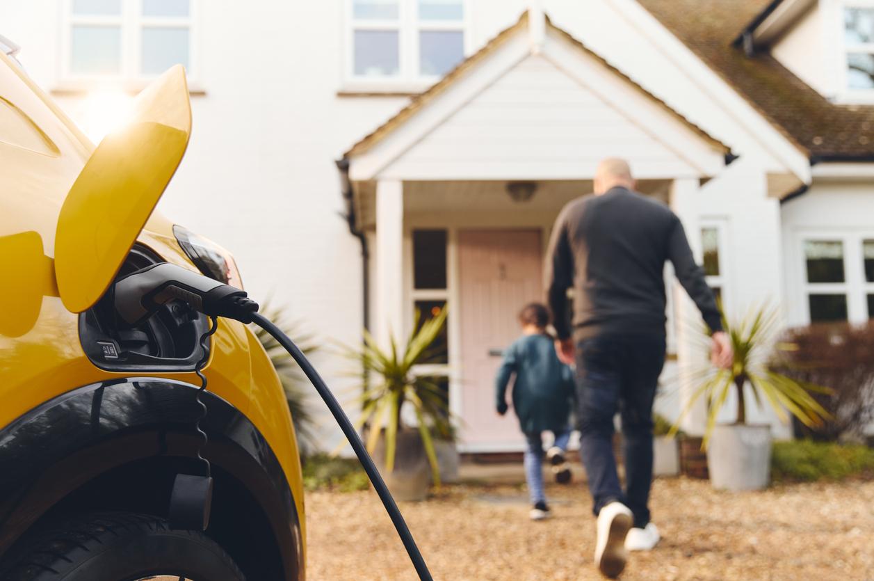 Electric car charging on driveway outside a house.