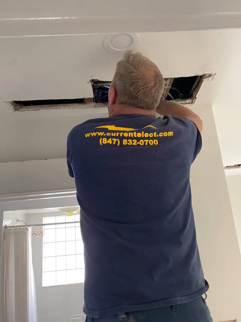 Electrician updating electrical wires in the ceiling of a house
